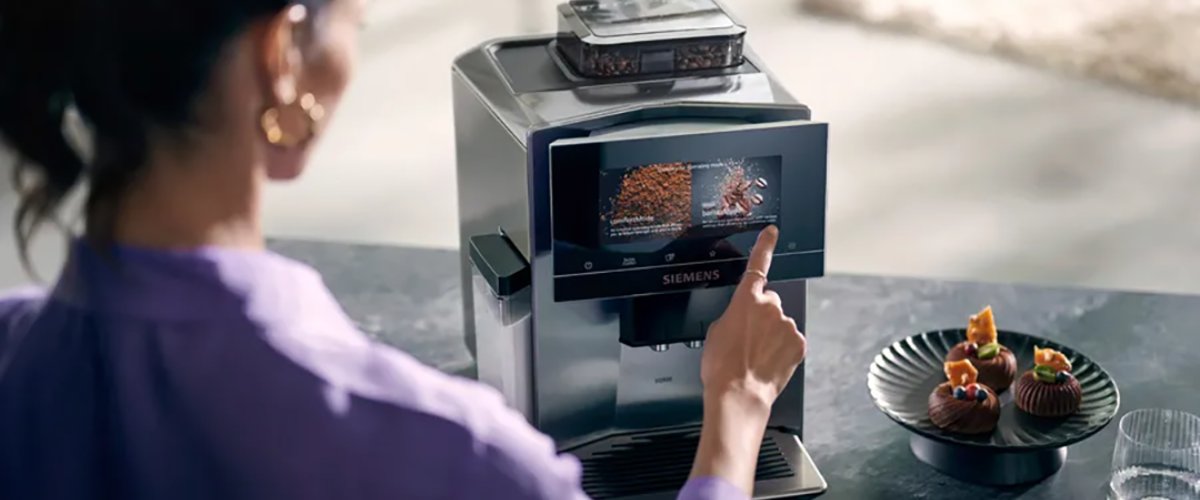 Sieviete pieskaras Siemens EQ900 automātiskā kafijas automāta skārienekrānam