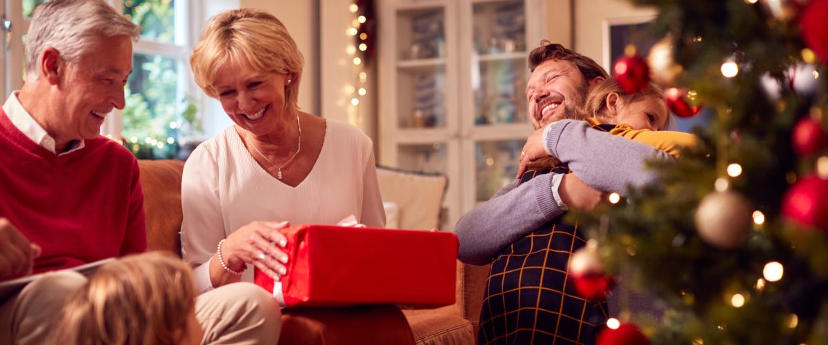 Ģimene atver iepakotu Ziemassvētku dāvanu vecākiem