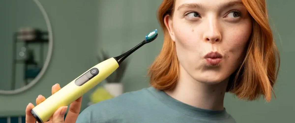 Sieviete rokā tur dzeltenu Beurer elektrisko zobu birsti