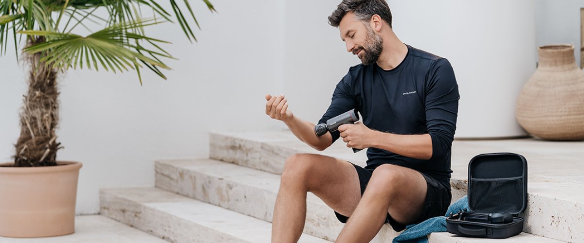 Vīrietis tur rokās Beurer masāžas ierīci un atslābina muskuļus