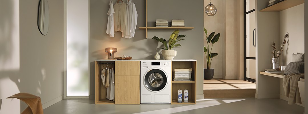 Miele priekšpuses ielādes veļas mašīna stilīgā un gaišā mājas veļas telpā
