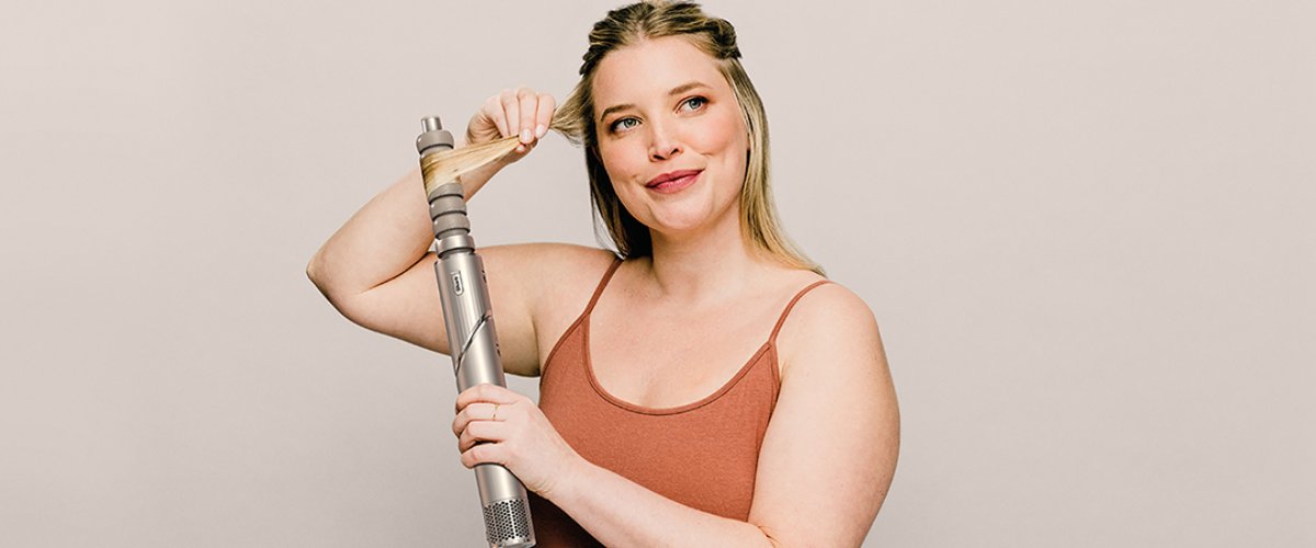 Sieviete izmanto Shark FlexStyle fēnu-lokšķēri matu žāvēšanai un loku veidošanai