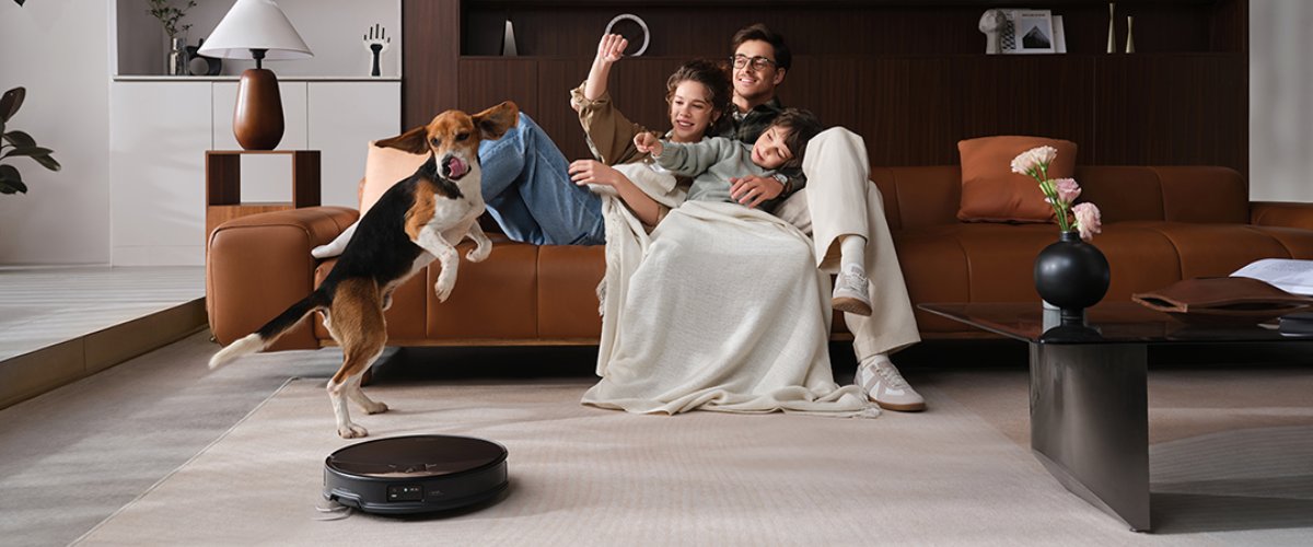 Robottolmuimejs darbojas viesistabā uz paklāja mājās, kur ir ģimene un mājdzīvnieks