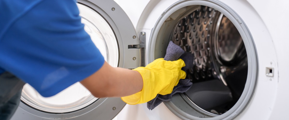 Priekšplānā roka tīra cepeškrāsni ar sūkli un tīrīšanas līdzekli